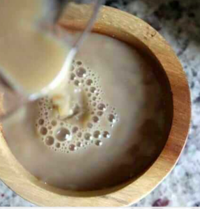 A drink of kava being poured into a wooden bowl